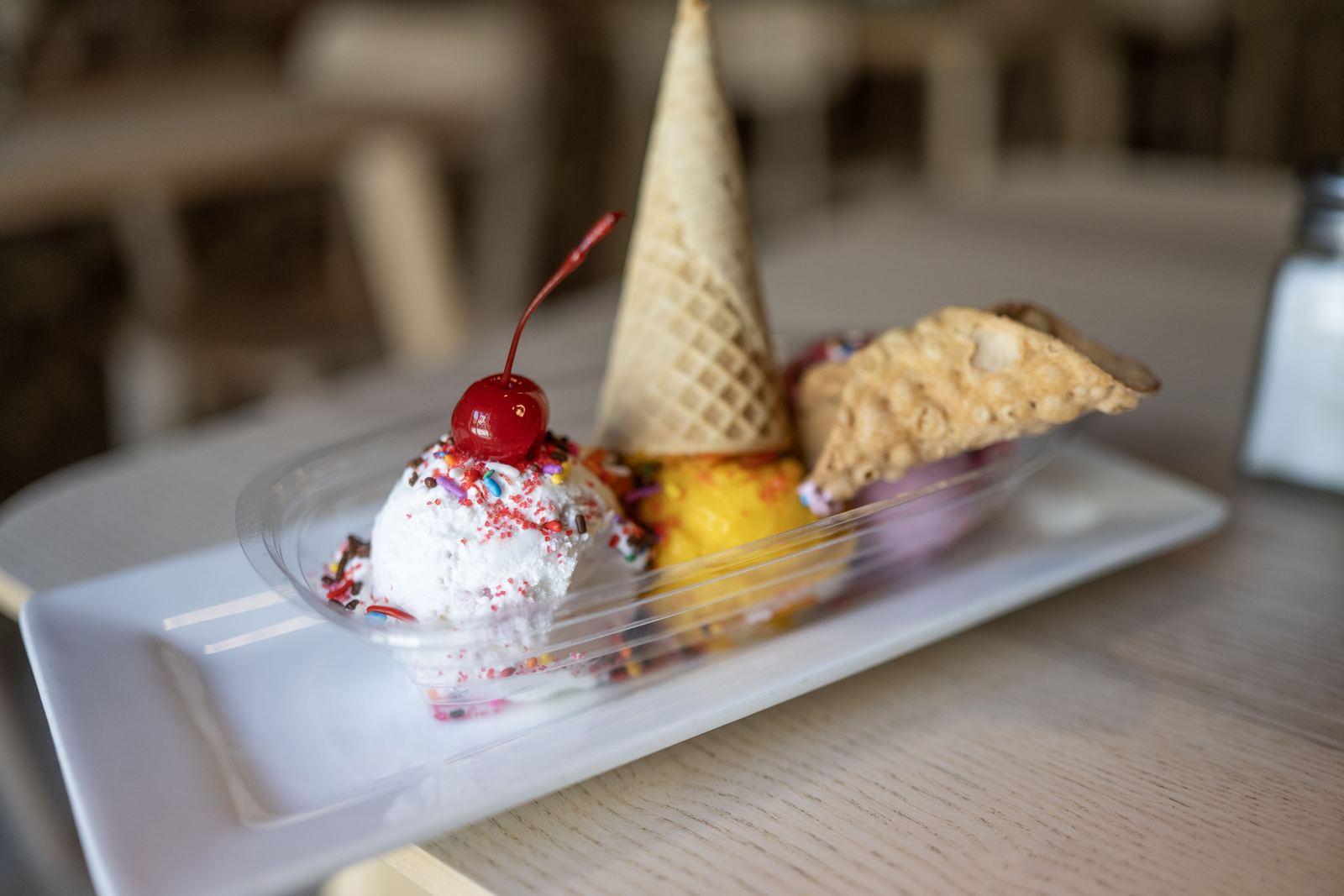 An ice cream sundae with a waffle cone and a cherry